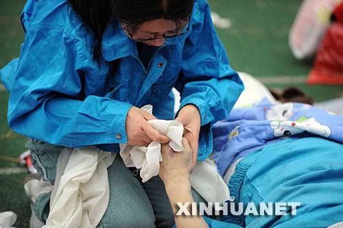 5月14日，張關蓉在擦拭丈夫譚千秋的遺體。 受汶川地震影響，四川省德陽市東汽中學教學樓坍塌。在地震發生的一瞬間，該校教導主任譚千秋雙臂張開趴在課桌上，身下死死地護著4個學生，4個學生都獲救了，譚老師卻不幸遇難。 新華社記者王建華攝