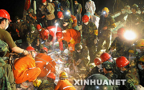 5月20日凌晨，在地震災區四川省綿竹市九龍鎮中心小學的廢墟里，搶險隊員正在搜尋幸存者。 5月19日下午5時許，空降兵某團、唐山搶險隊、西南石油搶險隊的數百名搶險隊員發現地震災區綿竹市九龍鎮中心小學的廢墟里有生命跡象。搶險隊員冒著余震的危險，采取輪流作業、分工負責的方式，堅持不懈地展開施救。 新華社記者 楊楹攝 