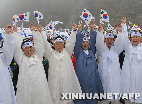 7月14日，大批韓國人在獨島（日本稱“竹島”）手舉國旗抗議。韓國外交通商部發言人文太暎當日發表聲明，強烈抗議日本在當天公布的中學教科書指導手冊中將獨島（日本稱“竹島”）表述為日本領土，并要求日本立即對有關內容進行修正。韓國外交通商部將采取召回韓國駐日本大使和召見日本駐韓國大使這兩項外交措施，就此問題向日本政府表示強烈抗議。 新華社/法新 