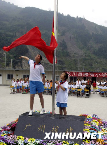 8月27日，映秀小學學生在板房校園內升起鮮艷的五星紅旗。 新華社發