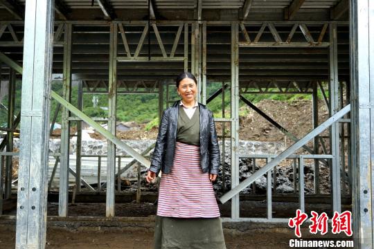 西藏隆子縣玉麥鄉位于中印邊境，是中國人口最少的行政鄉，全鄉56戶農牧民將于今年搬遷至新房。圖為7月14日，玉麥鄉群宗站在框架已經搭建好的新房門前，喜笑顏開。　江飛波 攝