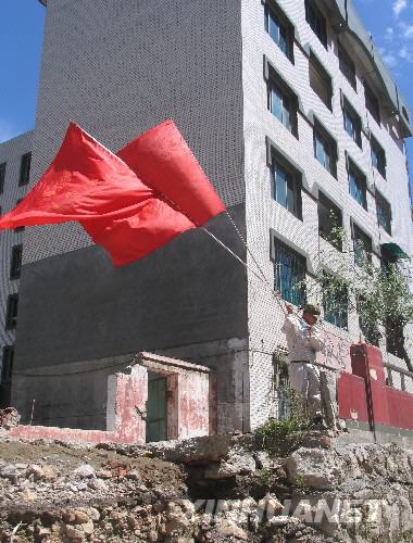  7月5日，一名防化兵高舉紅旗在北川縣城內行走。當日，記者經特許進入地震重災區北川縣城采訪，用相機記錄下北川縣城的現狀。 